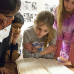 four students look at a book in an archive